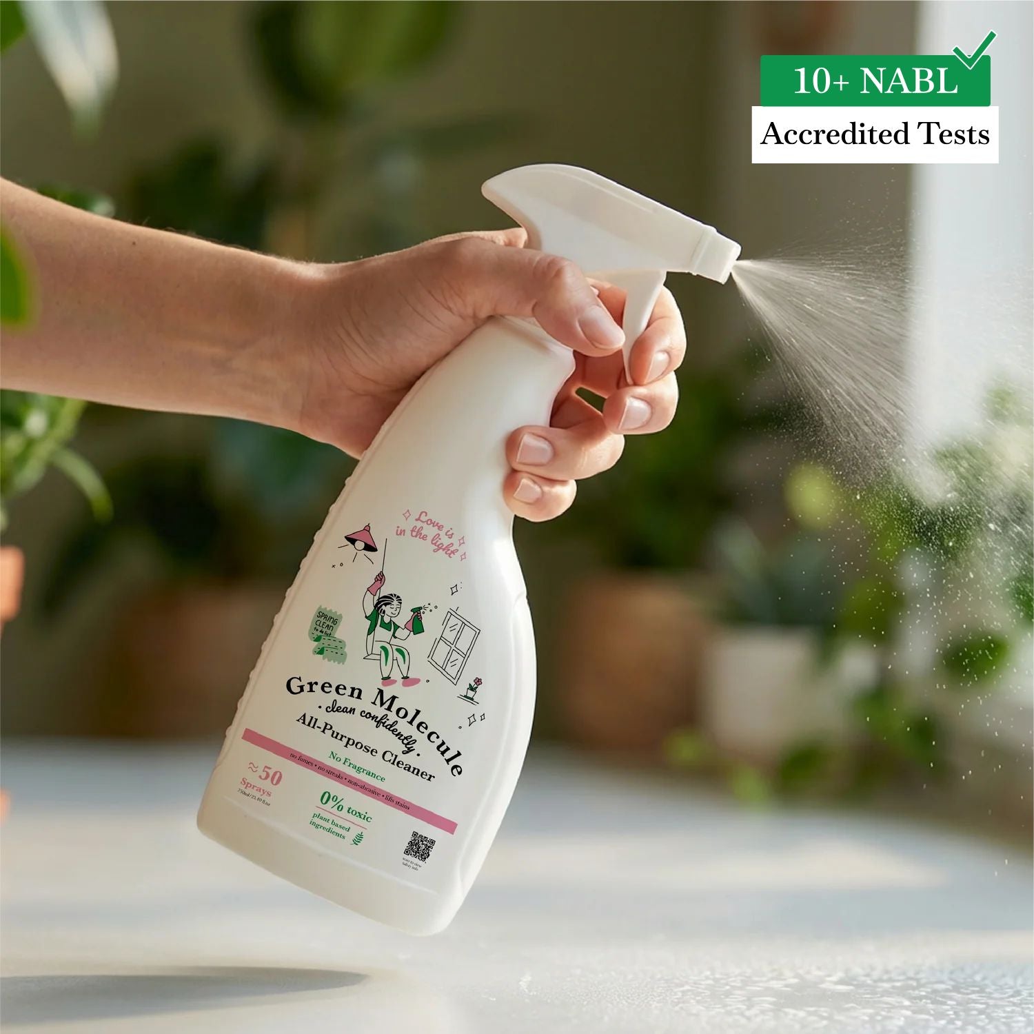 Hand spraying Green Molecule multi-purpose cleaner on a kitchen counter in a bright modern home, highlighting alcohol-free daily surface cleaning.